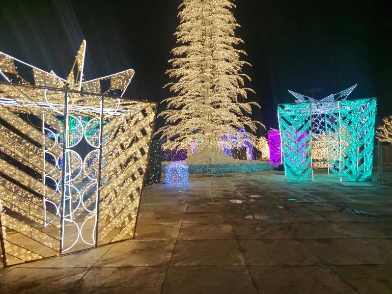 Illuminated gift-shaped structures and a golden Christmas tree along the Enchant Lite visitor route