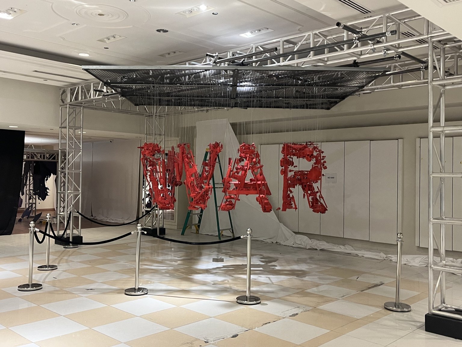 The same red suspended artwork spells WAR from another viewpoint