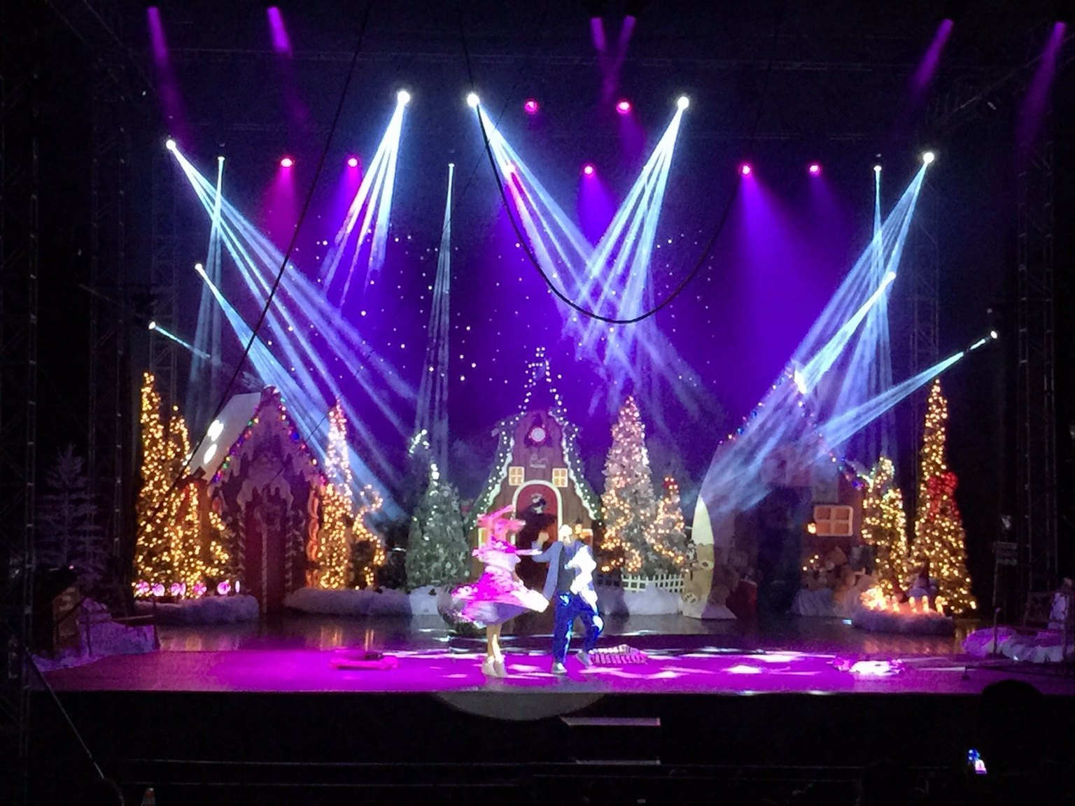 Santa Circus performers on a Christmas-themed stage under purple and white lighting
